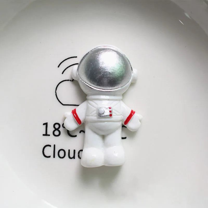 Miniature d'astronaute en décoration sur une assiette blanche, avec un casque argenté et une combinaison blanche aux accents 