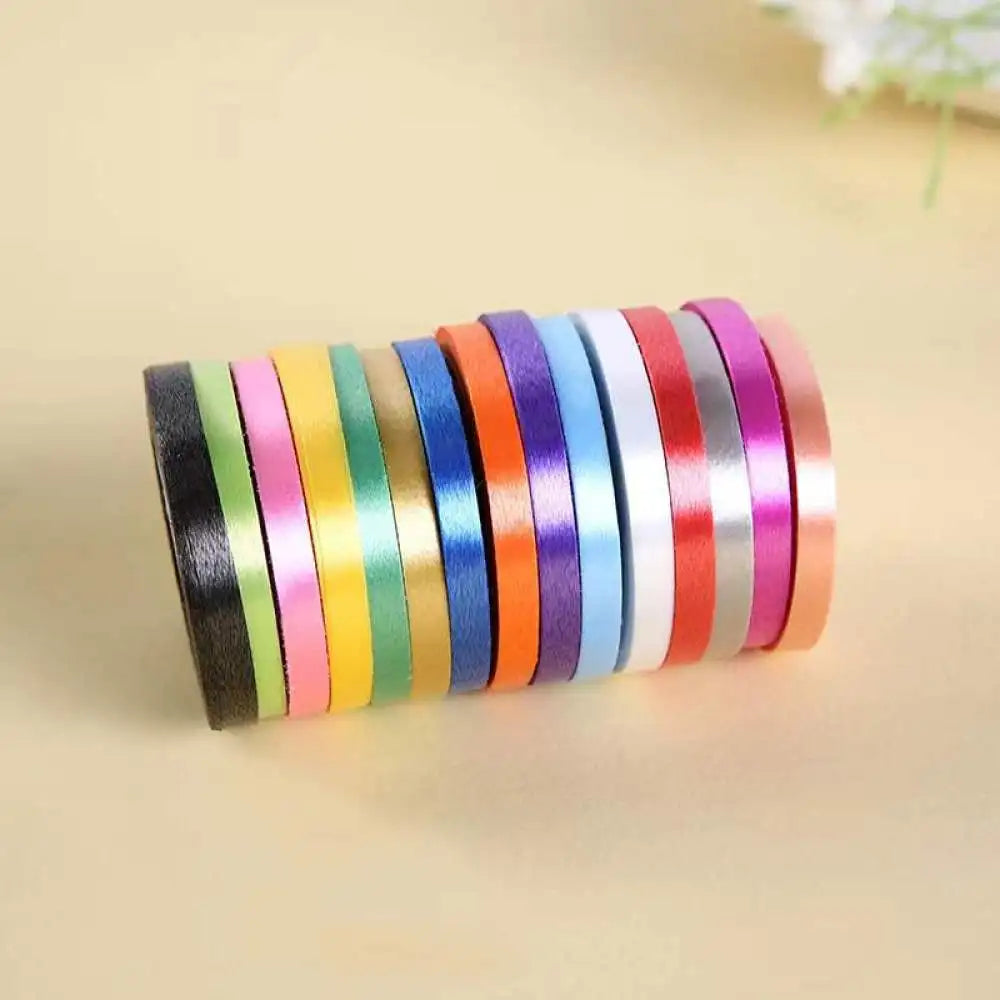 A roll of colorful satin balloon ribbons in various shades of pink, green, blue, and orange.