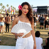 A woman wearing a white top and pants holds a silver glitter folding fan.