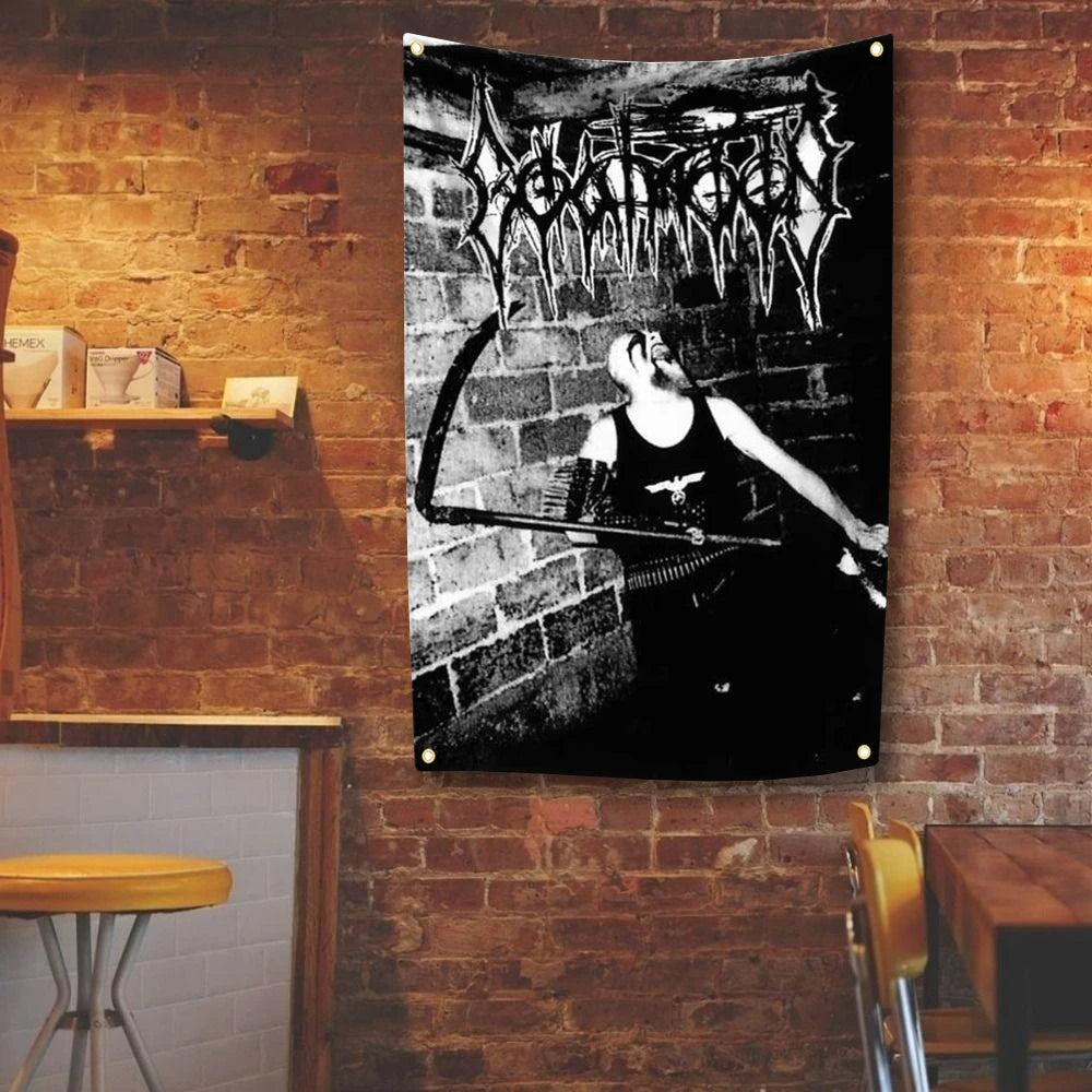 A black and white tapestry featuring a metal band logo and a figure playing a guitar hanging on a brick wall.