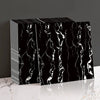 Black marble peel-and-stick wall panels with white veining displayed on a white surface.