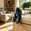 A dark gray 3D-printed gorilla figurine sitting on a wooden surface indoors.
