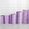 A row of four cylindrical spandex stands in varying heights and a purple glitter fabric, displayed against a white paneled wa