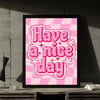 A framed wall art print featuring the pink checkered pattern and the text Have a nice day in bright pink lettering.