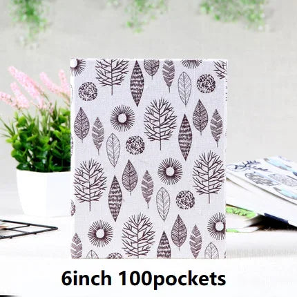 A white fabric pouch with a repeating pattern of various leaf shapes for storing photos.