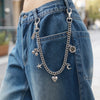 Gros plan d'un charm de sac en chaîne argentée suspendu du poche arrière d'un jean bleu en denim.