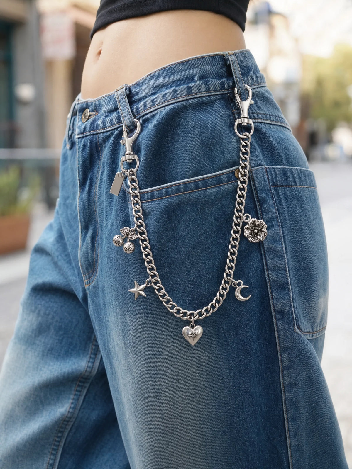 Gros plan d'un charm de sac en chaîne argentée suspendu du poche arrière d'un jean bleu en denim.