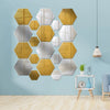 A display of 12 self-adhesive hexagon mirror wall decor stickers in gold and silver tones mounted on a light blue wall.