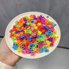 A pile of colorful flower and star hair claw clips for kids on a white plate.