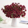 A bouquet of deep red silk gerbera daisy artificial flowers in a white pitcher.