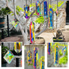A set of seven crystal prism sun catchers hanging from a tree branch in an outdoor garden setting.