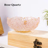 A delicate rose quartz bowl with gold flecks displayed on a light wooden surface.