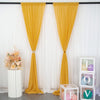 A yellow chiffon backdrop curtain hanging in front of a white wall with floral arrangements and decorative boxes.