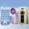 A purple mini handheld fan is displayed on a white surface next to its packaging box.