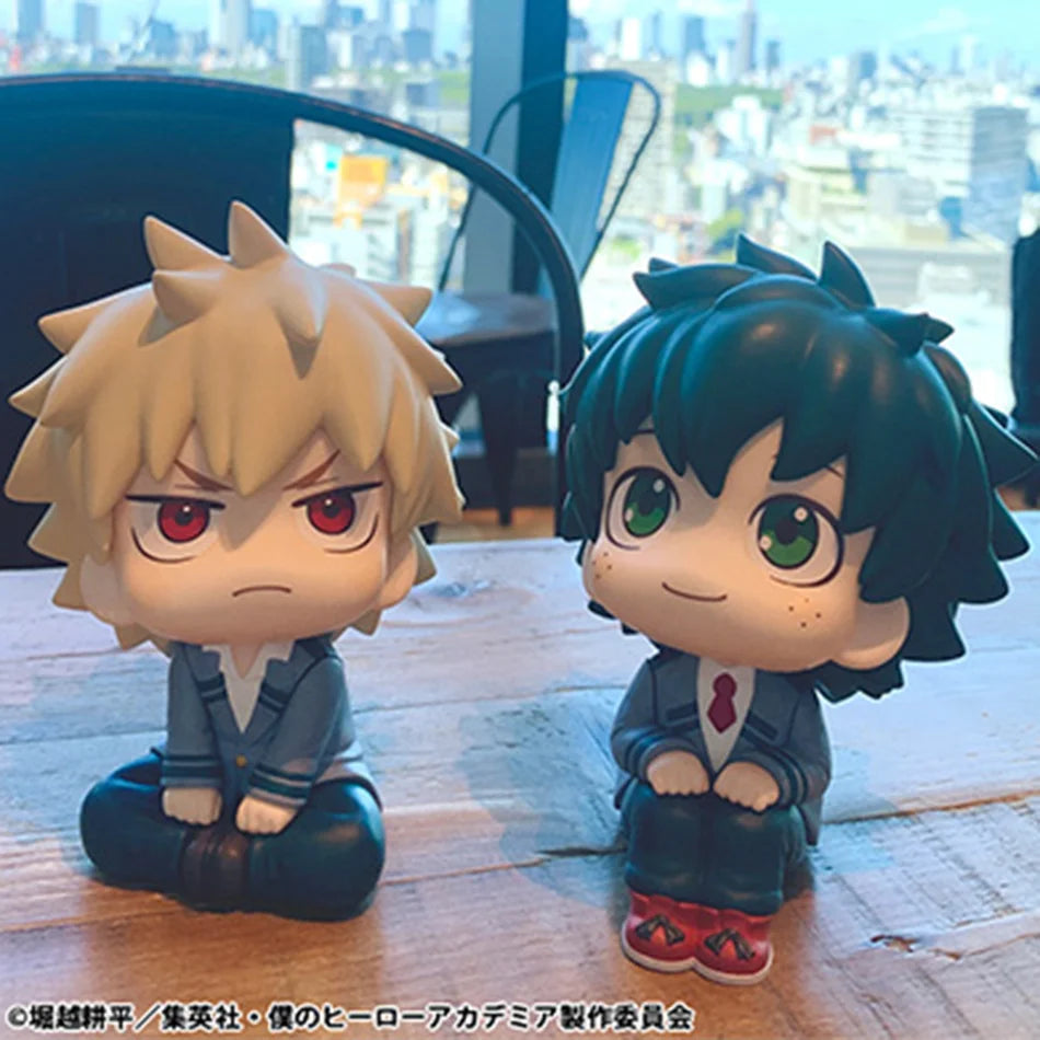 Chibi collectible figures of My Hero Academia characters Izuku, Bakugo, Shoto, and Toga displayed on a wooden surface.