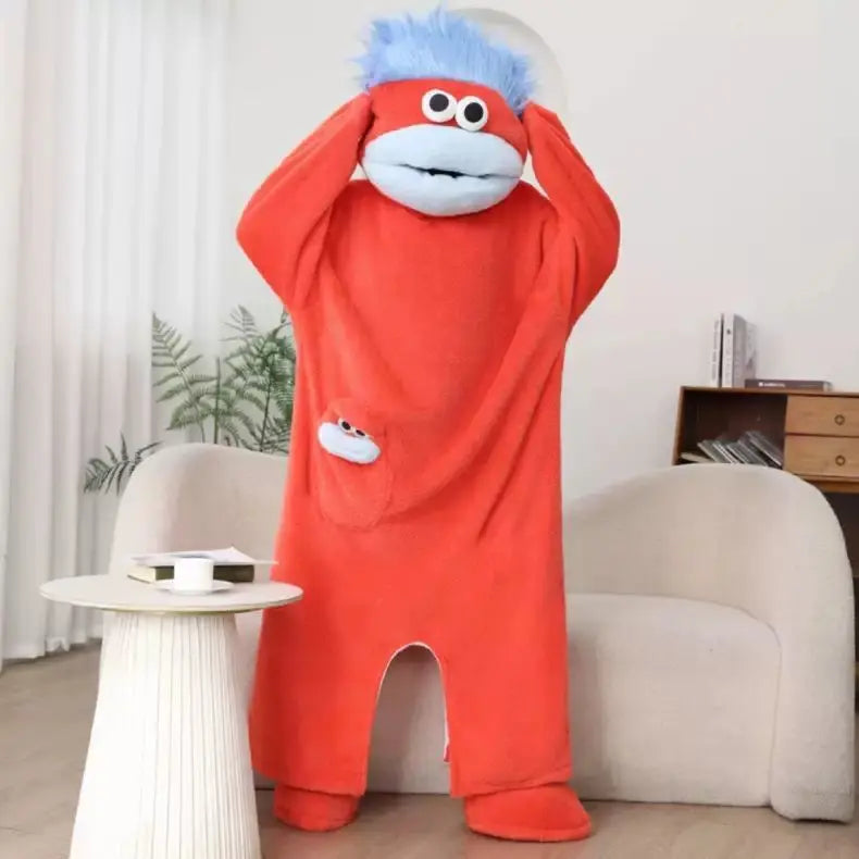 An orange coral fleece hooded sleepsuit resembling a monster with blue hair and large eyes.