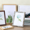 A set of five rustic wooden photo frames displaying floral and botanical prints on a light background.