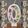 A glitter number candle shaped like zero decorated with colorful candy beads for a birthday celebration.