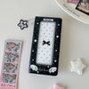 A black photo booth album with a clear window featuring white stars and a black bow, next to some star-shaped accessories.
