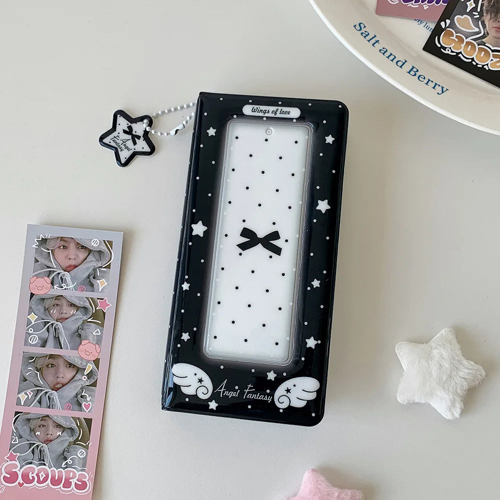 A black photo booth album with a clear window featuring white stars and a black bow, next to some star-shaped accessories.