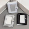 A set of two mini photo card binders, one white and one black, displayed on a gray surface.