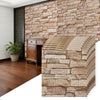 A close-up of 3D foam brick wallpaper panels in earthy tones mounted on a textured stone wall.