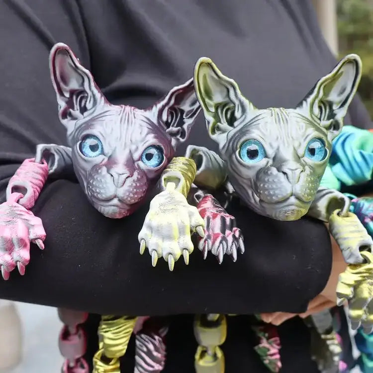 A realistic gray Sphynx cat fidget toy with blue eyes is held in a person's hand.