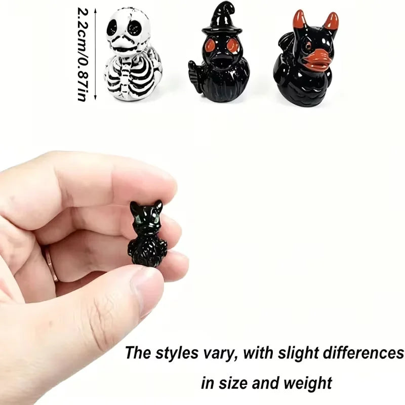 Un set de trois figurines d'Halloween miniatures : un fantôme rayé, une chauve-souris noire et un chat noir, à côté d'une mai