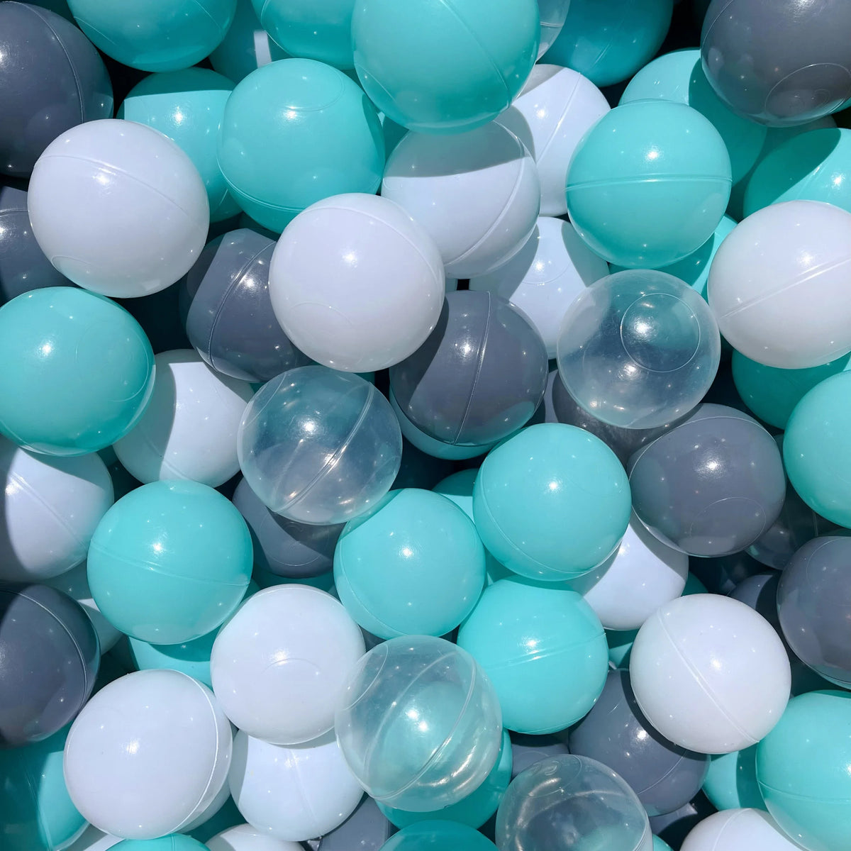 A close-up view of a 50-pack of colorful, translucent and opaque balls in shades of light blue, white, and gray.