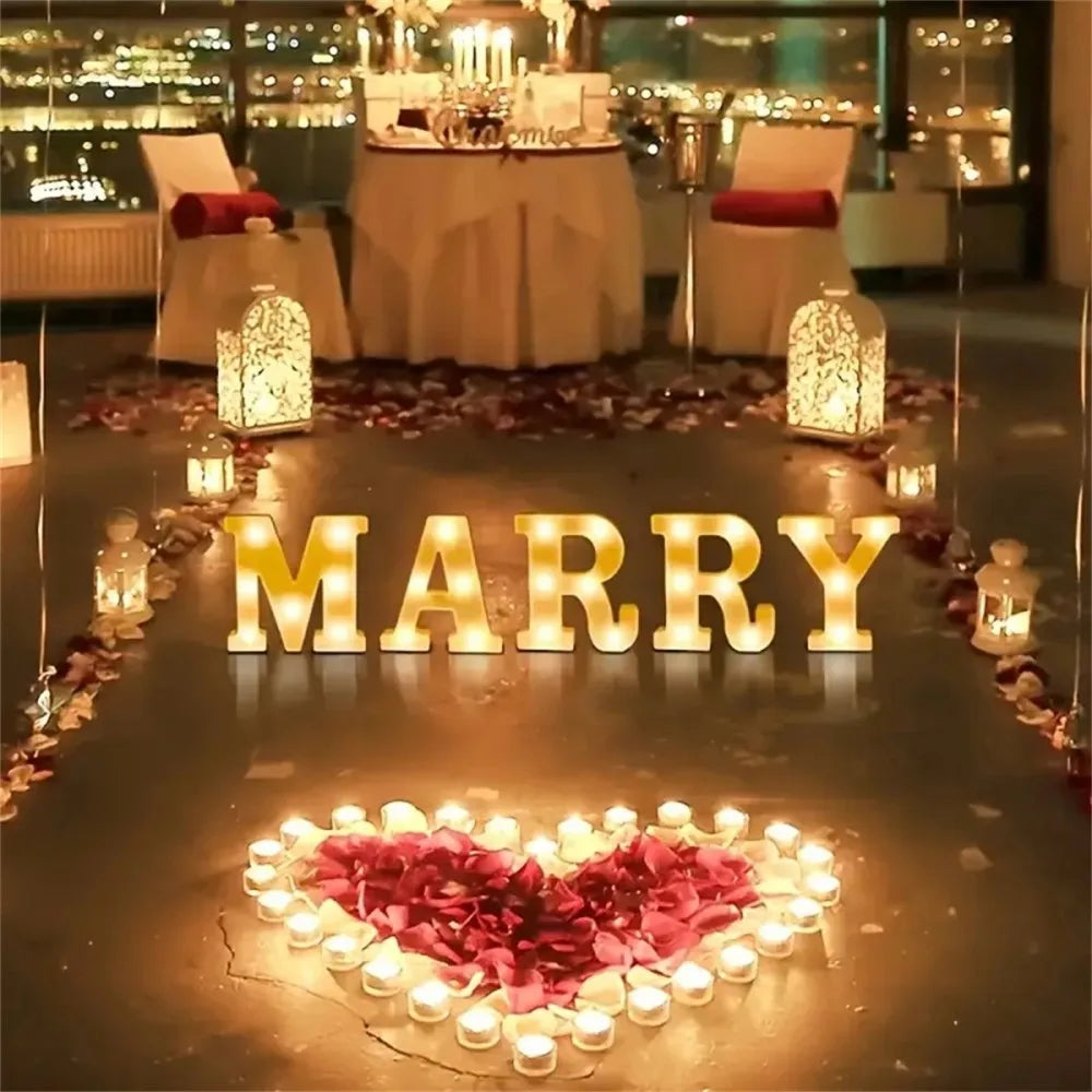 Golden letter lights spelling MARRY illuminate a path leading to a heart shape made of pink petals.
