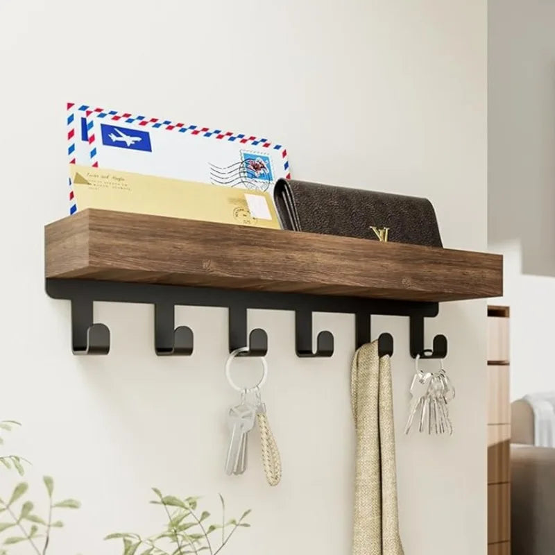A rustic wooden floating shelf with hooks displaying various paper items and clothespins.