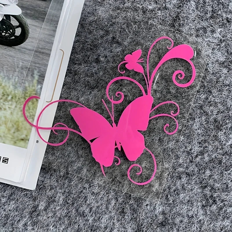 A bright pink vinyl butterfly sticker with swirling lines is placed on a gray, textured surface.