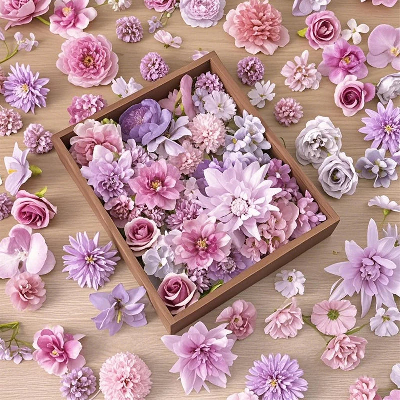 A close-up of various pink, purple, and mauve silk artificial flower heads scattered on a wooden surface.