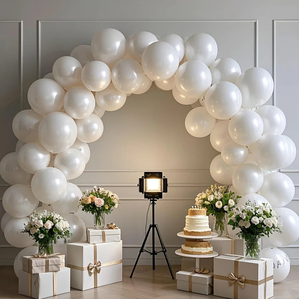 A white balloon arch decorated with pearl white latex balloons and floral arrangements for a wedding or party backdrop.
