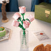 A bouquet of pink rose building blocks in a glass vase on a white table.