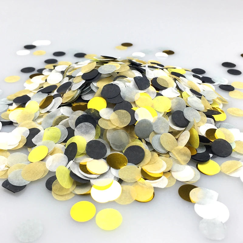 A pile of multicolor gold, silver, and black paper confetti scattered on a white surface.