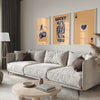 A modern living room featuring a light sofa, wooden coffee table, and framed art prints on the wall.