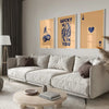 A modern living room features a light sofa, wooden coffee table, and framed art prints on the wall.