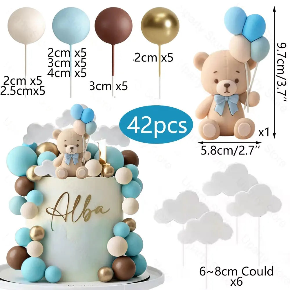 A teddy bear cake topper featuring blue and gold foam balls and clouds, with various sized balloon toppers shown.