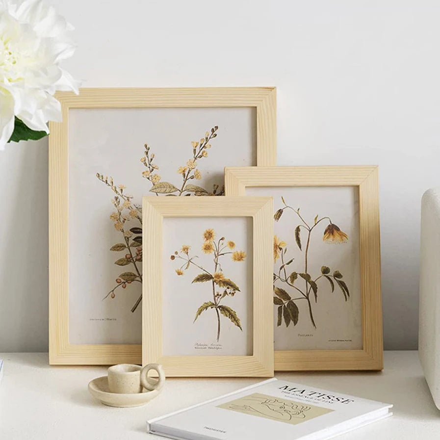 A collection of natural wood picture frames displaying dried botanical illustrations on a white surface.