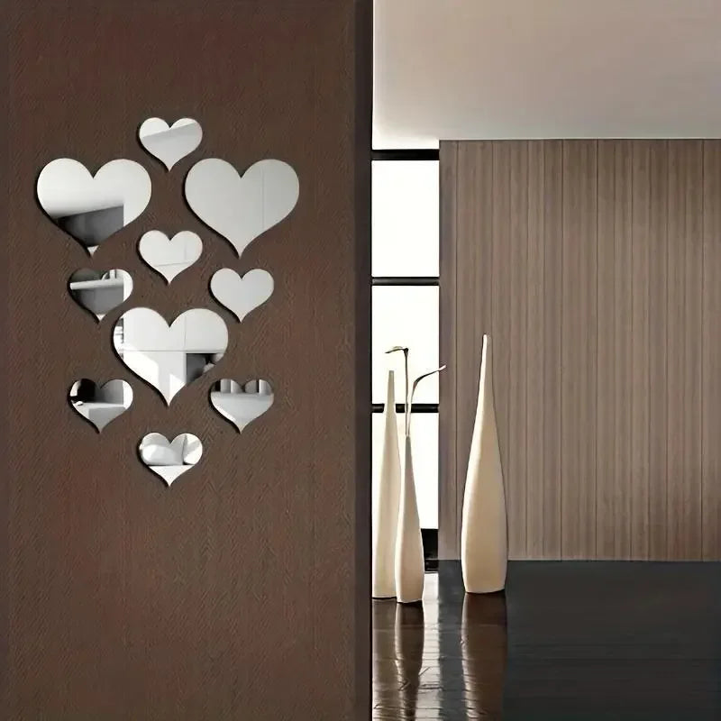 A set of silver heart-shaped mirror wall stickers mounted on a brown wall next to a modern interior with light wood paneling.