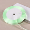 A roll of light green satin ribbon on a white spool, ready for gift wrapping or DIY crafts.