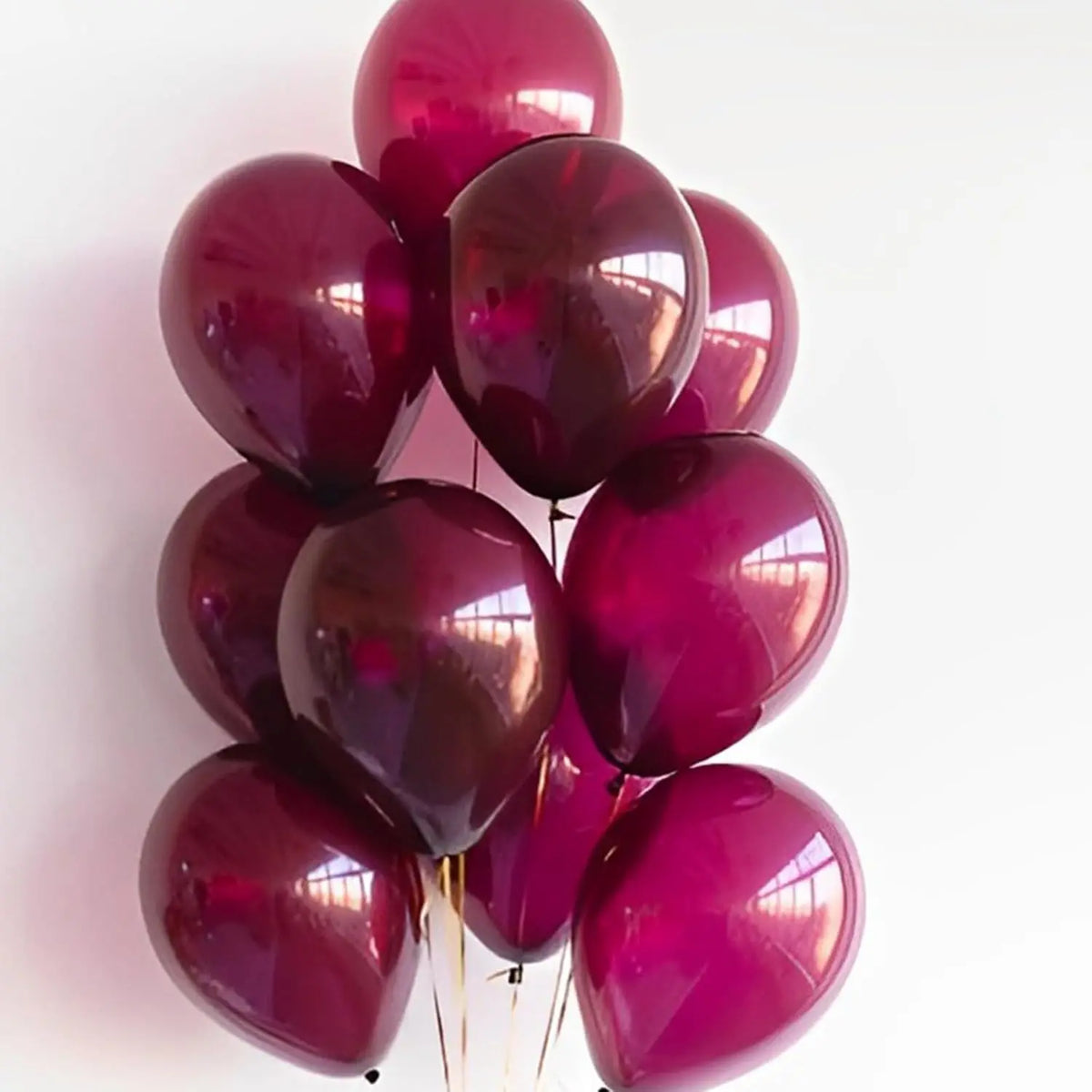A cluster of glossy burgundy red latex balloons tied together for a celebration.