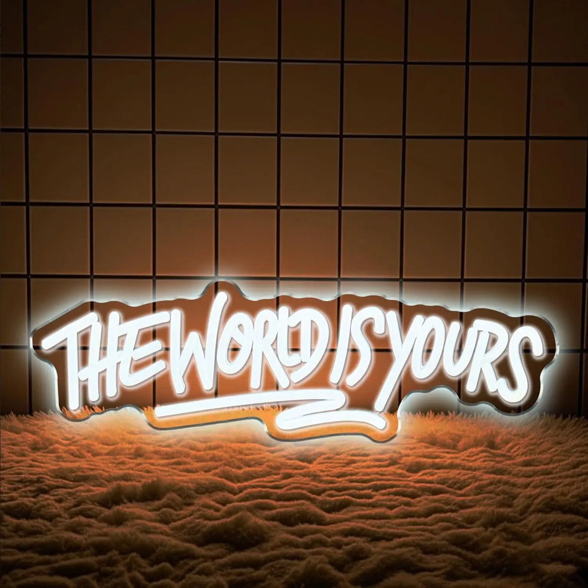 A glowing neon sign spelling out THE WORLD IS YOURS rests on a textured surface.