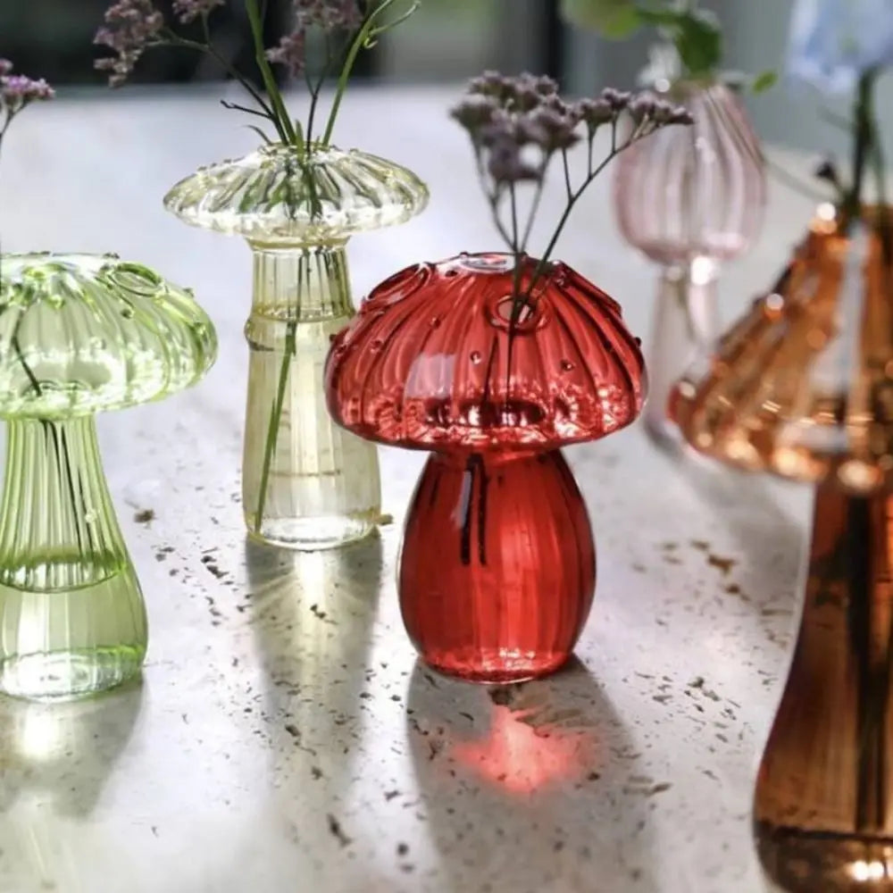 A collection of glass vases shaped like mushrooms in translucent jelly colors, including green and pink.