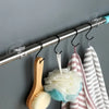 A silver curtain rod holds various fabric and brush holders for no-drill installation.