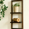 A dark wood floating wall shelf with two tiers displaying a potted plant and a wooden log.