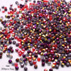 A pile of faceted bicone glass beads in mixed colors including red, purple, and amber tones.