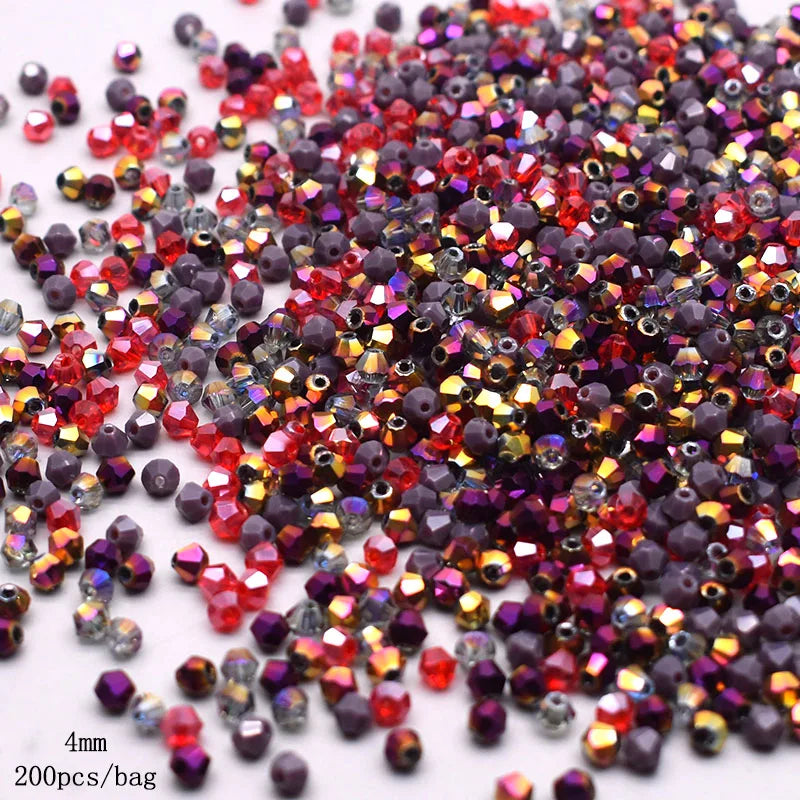 A pile of faceted bicone glass beads in mixed colors including red, purple, and amber tones.