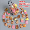 Ten plastic capybara mini figures inside a clear suitcase with soft glow effect